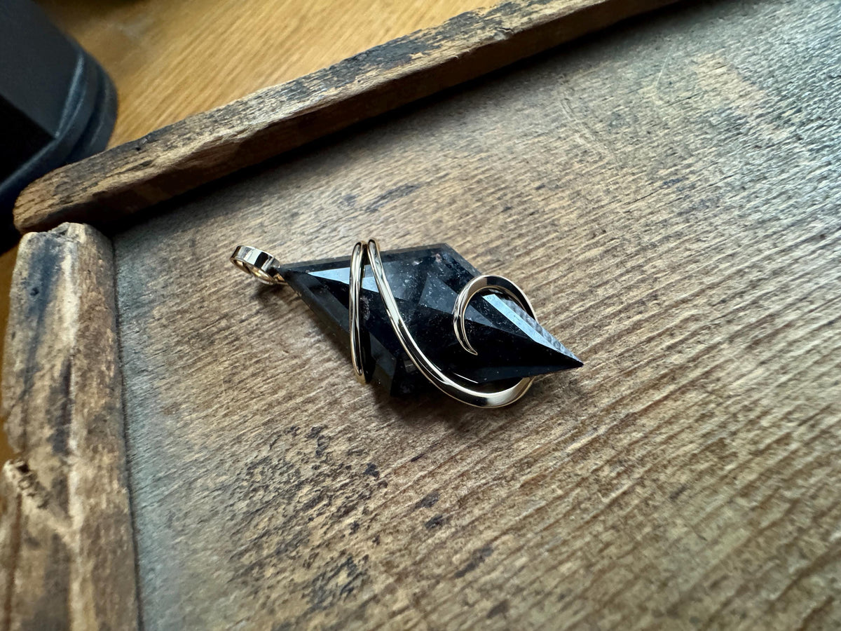 Faceted nuummite in 14k gold pendant
