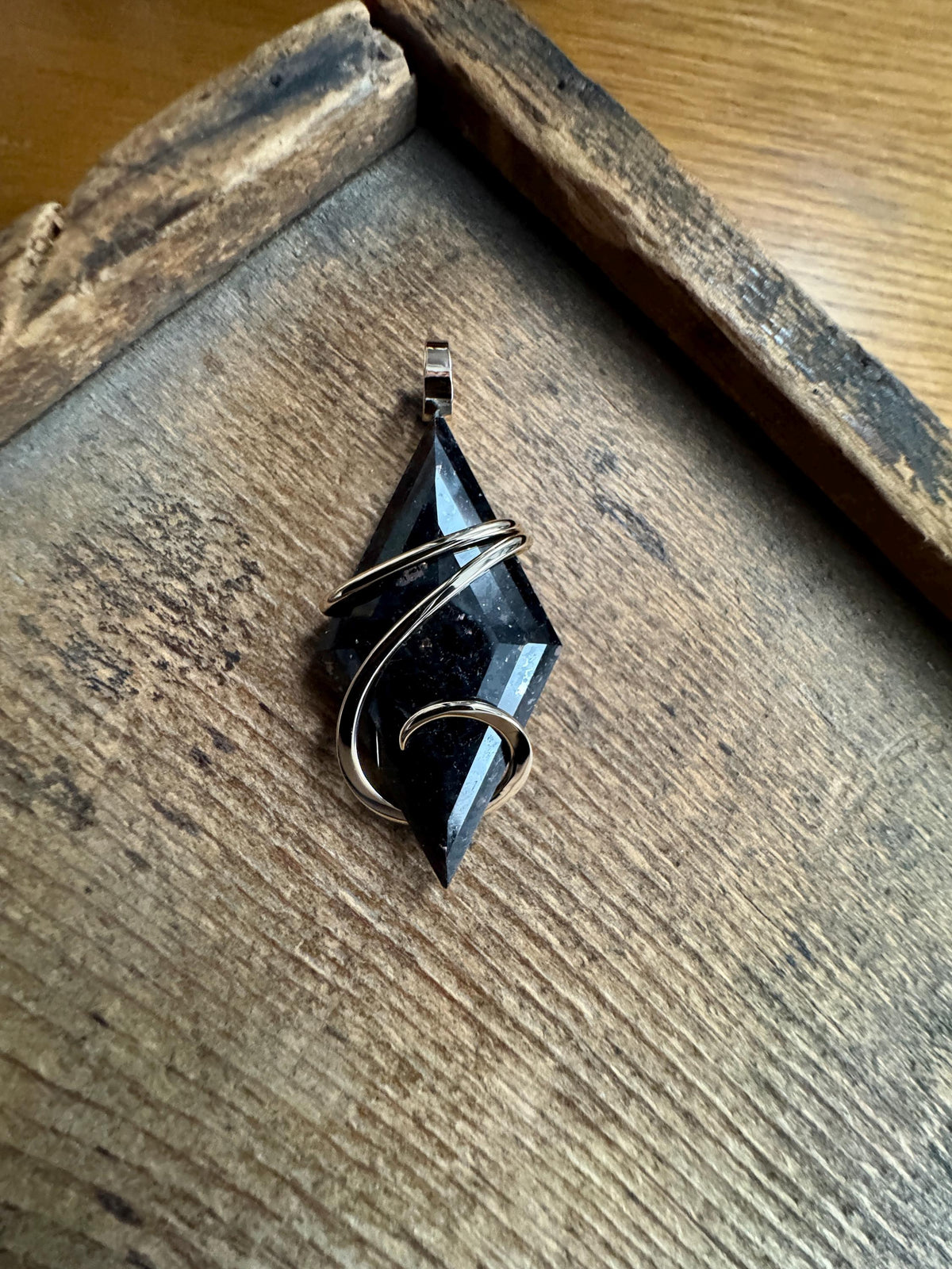 Faceted nuummite in 14k gold pendant